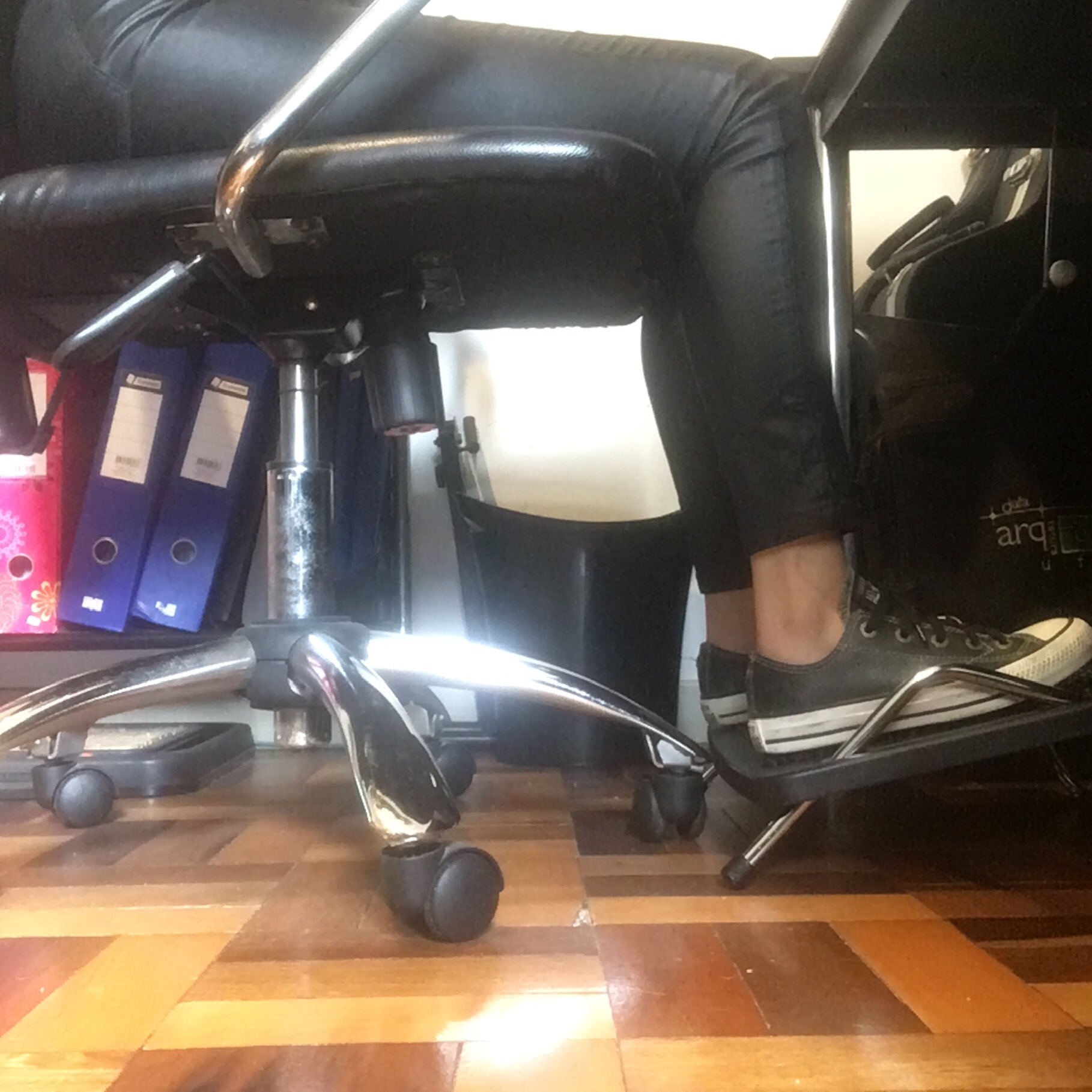 Imagem parcial de uma pessoa sentada, mostrando as pernas e os pés, apoiados em suporte próprio.